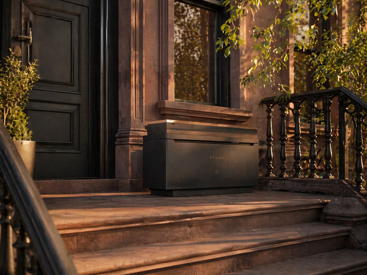 The Stoop delivery vault on the top landing of a Brooklyn brownstone at golden hour, beside a paneled black door and wrought-iron balusters.